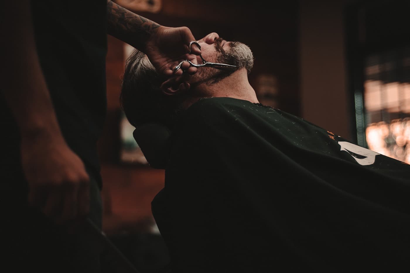 A customer reclined in the chair for a beard trim