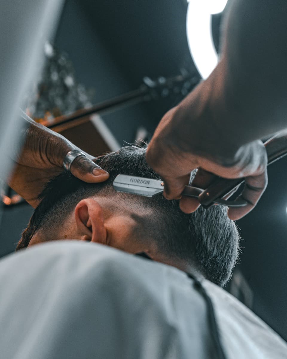Barber using a straight razor to line up a haircut